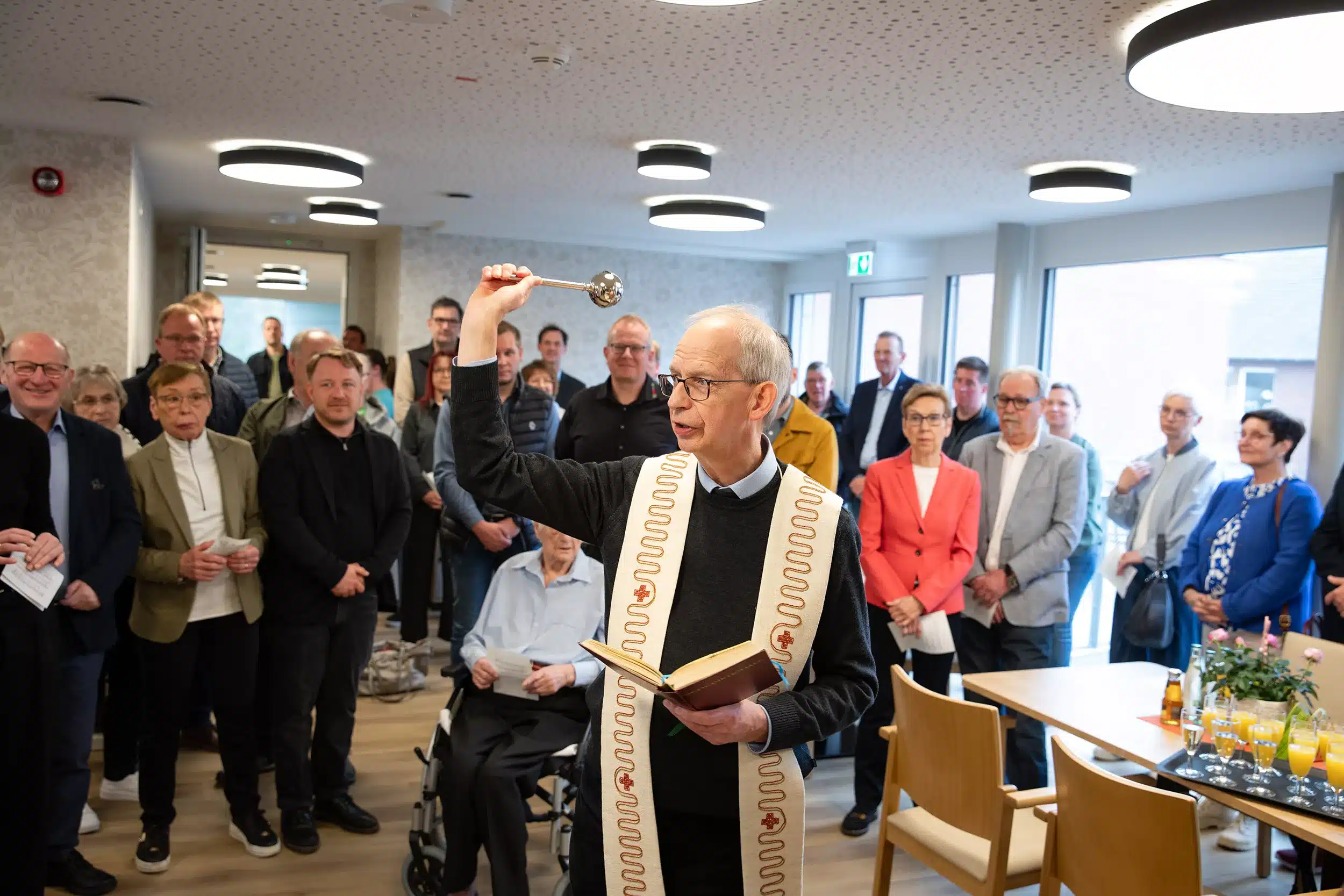 Priester segnet die neue Tagespflegeeinrichtung der Firma Leusbrock Pflege. Man sieht eine große Gruppe Menschen bei der Eröffnung der Tagespflegeeinrichtung der Firma Leusbrock Pflege.